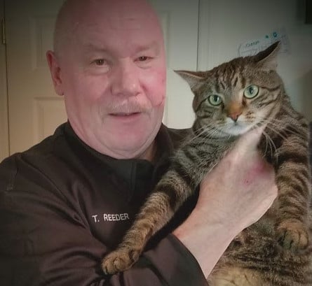 Bio photo of Tim Reeder in a dark shirt holding a tan and black cat